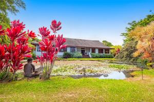 a house with red flowers in front of a yard at The Aloha Villa - 30-Night Minimum in Honokaa