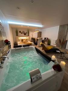 a large swimming pool in a room with a living room at Grand Studio magnifique avec Spa privatif illimité in La Bassée