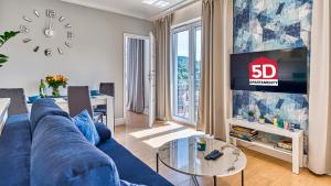a living room with a blue couch and a tv at Apartament BlueSky - 5D Apartamenty in Świeradów-Zdrój