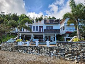 a large white house with a stone wall at Paradise Cove Villa 2BR Oceanfront Haven, Private Infinity Pool & Jacuzzi, King Bed, 2 Full Beds, 2 Extra Dutton Beds, WiFi, Private Parking in Sigayan