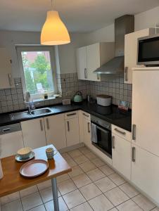 a kitchen with white cabinets and a table in it at Ferienwohnung Stadtgracht in Nordhorn