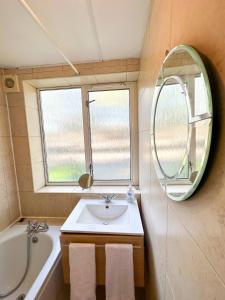 a bathroom with a sink and a tub and a mirror at 36 O’Leary square in London