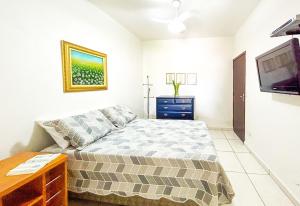 Un dormitorio pequeño con una cama y un televisor. en Casa com churrasqueira e piscina em Itanhaem, en Itanhaém
