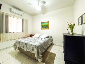 Un dormitorio con una cama y un televisor de pantalla plana. en Casa com churrasqueira e piscina em Itanhaem, en Itanhaém