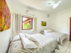 um quarto com 2 camas e uma janela em Casa com churrasqueira e piscina em Itanhaem em Itanhaém