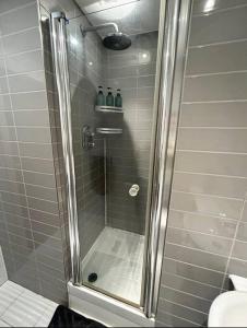 a shower with a glass door in a bathroom at 2 bed apartment close to station with parking in London