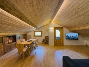 una grande camera con soffitto in legno, tavolo e sedie di Bormio House con vista pista Stelvio a Bormio