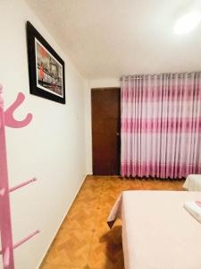 a room with a bed and a pink curtain at Female Accommodation Experience in front of Lima Airport in Lima