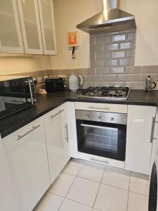 a kitchen with white cabinets and a stove top oven at Your Own Ground Floor Apartment in Central Woking in Woking