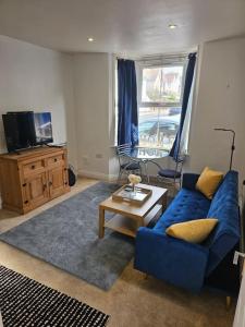 sala de estar con sofá azul y mesa en Your Own Ground Floor Apartment in Central Woking en Woking