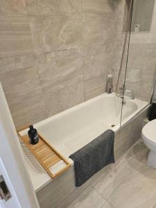 a bathroom with a white tub and a toilet at Your Own Ground Floor Apartment in Central Woking in Woking