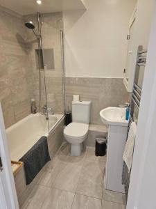 Your Own Ground Floor Apartment in Central Woking في ووكينغ: حمام مع مرحاض وحوض استحمام ومغسلة