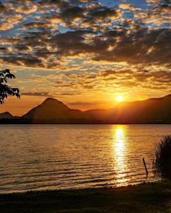 um pôr-do-sol sobre um corpo de água com montanhas em Casa temporada maricá em Maricá