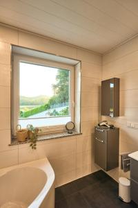 baño con bañera y ventana en 118qm Traumzeit Residences am National Park Birkenfeld - Perfekt für bis zu 4 Personen en Ellweiler