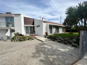 a white house with a stone wall and a driveway at CasaAnabela in Póvoa de Varzim