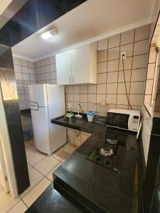 a small kitchen with a stove and a refrigerator at diRoma Fiori - Apartamentos JN in Caldas Novas