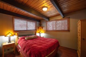 a bedroom with a red bed with two lamps and two windows at Leavenworth Mountain View Cabin w/ Space to Hike in Leavenworth