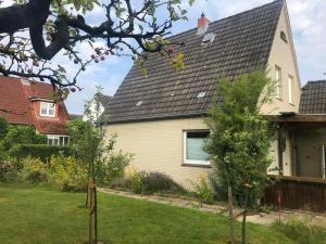 een huis met een zwart dak en twee bomen in de tuin bij FeWo-Schnoor in Lübeck