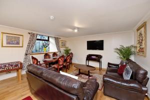 a living room with a leather couch and a table at Inviting 9-Bed House in Aberdeen in Aberdeen