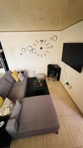 sala de estar con sofá y reloj en la pared en Senderos Apartment, Self Check- in, Airport SJO 5 MIN, en Santiago Este