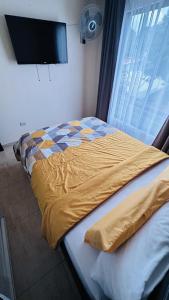 a bed with a yellow comforter sitting next to a window at Senderos Apartment, Self Check- in, Airport SJO 5 MIN in Santiago Este