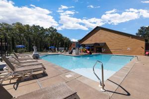 a swimming pool with two chairs and a playground at Rock and Timber Lodge in Branson