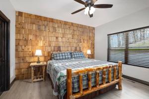 1 dormitorio con 1 cama y pared de madera en Rock and Timber Lodge en Branson