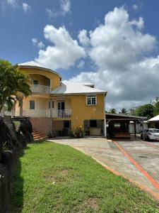 a large yellow house with a parking lot at Guadeloupe Guesthouse in Port-Louis