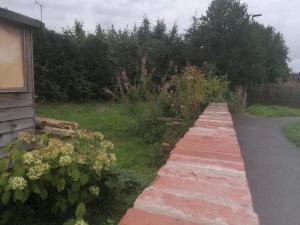 un camino de ladrillo que conduce a un jardín con flores en The Old Barn, Cosy Townhouse in Leominster, en Leominster