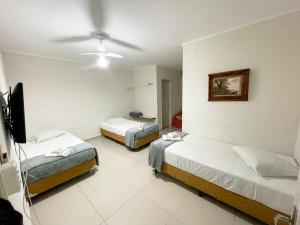 a hotel room with two beds and a flat screen tv at Central Park Hotel Residence in São Carlos