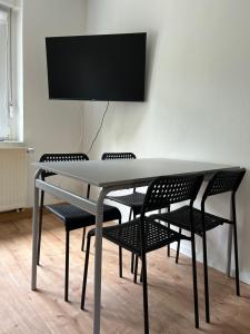 a table with chairs and a television on a wall at Monteurwohnung I WLAN I Einzelbetten in Burgneudorf