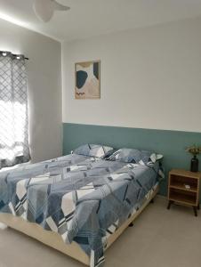 a bed with a blue and white comforter in a bedroom at Apartamento no Condomínio Vila das Águas in Estância