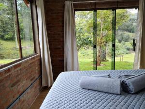 a bedroom with a bed and a large window at Refúgio da Família Koch - casa de campo in Sinimbu