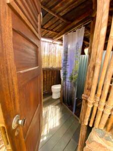 a bathroom with a toilet and a wooden door at Magical Treehouse in Lagos