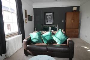 a living room with a leather couch with green pillows at City Centre Bolt Hole Exeter in Exeter