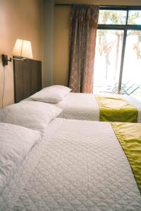 a row of three beds in a room with a window at HOTEL MANTA BEACH MADRIGAL in Manta