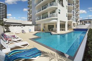a hotel room with a pool and chairs at Aqua Vista Resort in Maroochydore