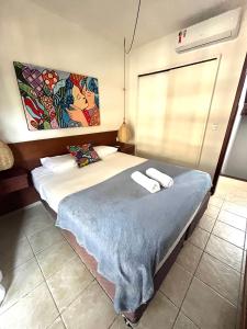 1 dormitorio con 1 cama con 2 toallas en Charmoso Chalé Triplex - Centro da Pipa en Pipa
