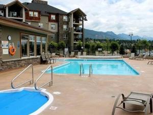 a pool at a resort with chairs and a building at Light N Airy, Pool, Hot Tub, Pets, Ground Floor in Invermere