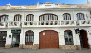 Edificio blanco con puertas marrones y balcón en HOSPEDAJE SARABIA en Sucre