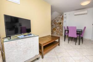 a living room with a table and a flat screen tv at House Neda in Ražanj