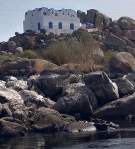 a building on a pile of rocks next to the water at HoneyMoonnaka Guest House Nubian ( بيت هانى ) in Aswan