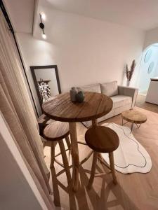 un tavolo e sgabelli in un soggiorno con divano di La perle du parc - Studio a Rocquencourt