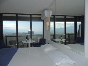 um quarto de hotel com uma cama e duas mesas e janelas em Orbi City Superhost em Batumi