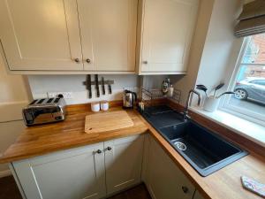 encimera de cocina con fregadero y ventana en Honeysuckle Cottage en Mountsorrel