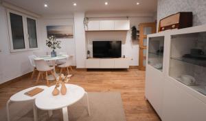 eine Küche und ein Wohnzimmer mit einem Tisch und einem TV in der Unterkunft La Concha Pearl Beach Apartment in San Sebastián
