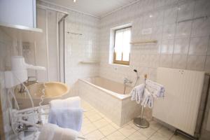 un bagno bianco con vasca e lavandino di Ferienhaus Maxi a Sankt Blasen