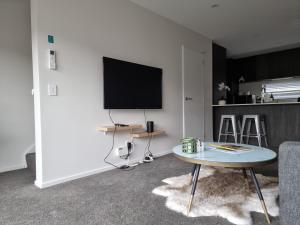 uma sala de estar com uma mesa e uma televisão de ecrã plano em Addington townhouse with carpark 8mins walk to Hagley park south em Christchurch
