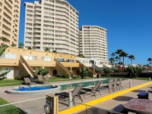 una piscina con sillas y edificios en el fondo en 2BD Beach Front Condo with Pool & More, en Rosarito