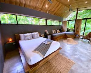 1 dormitorio con 1 cama y sala de estar con ventanas en Villas Kalei, en Playa Grande